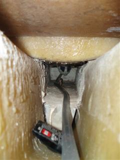 This is a view looking from under the V berth aft.  The pipe is our water pipe from the tank which is stowed in the forward V.  The whitish block is part of the glassed in lead ballast. The other object is a cockroach bait.<br />The step is the one under the porta pottie which you can see in the previous photo.