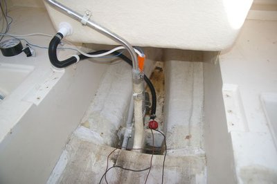 View inside bilge area, showing new pump and drain tube for older hand pump, plus new wiring conduit, leading to inner starboard cabin bulkhead (where I will mount the electrics)